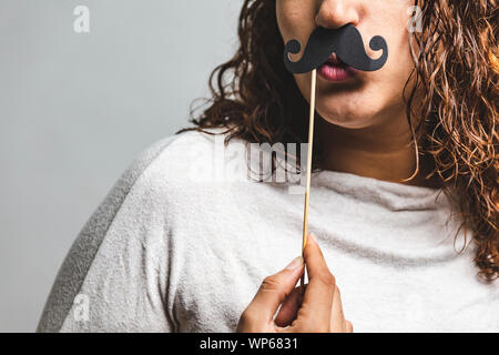 Close up portrait of head shot of young girl wearing fake moustaches - Girl holding funny moustache sur stick Banque D'Images