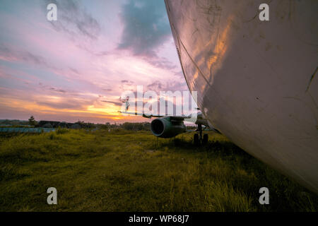 Guy marcher sur l'aile d'un avion abandonné au milieu de nulle part pendant beau coucher du soleil Banque D'Images