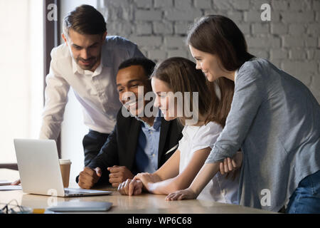 L'équipe de divers employés souriants regardant webinar sur le laptop Banque D'Images