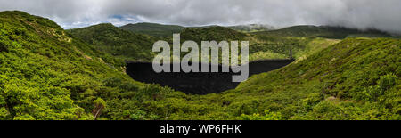 Paysage de Lagoa Comprida caldera crater lake noir foncé entourée par la végétation verte et avec un ciel d'orage sur l'Ilha das Flores Island, à l'un Banque D'Images