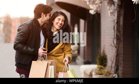 Shopping ensemble. Homme murmurant à l'oreille femme Banque D'Images