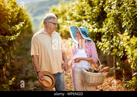 Happy senior couple walking in entre les rangées de vignes Banque D'Images