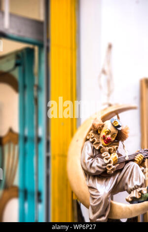 Une marionnette clown assise sur une demi-lune devant un magasin; Toledo, Espagne. Banque D'Images