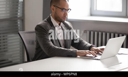 Jeune homme sérieux travaillant avec un ordinateur portable dans la salle de réunion. Banque D'Images
