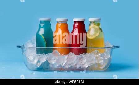 Différentes boissons aromatisées detox en bouteilles de verre sur bleu Banque D'Images