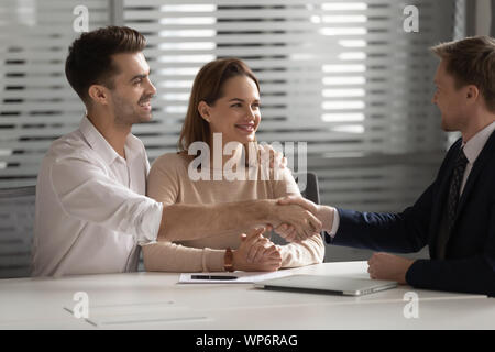 Famille heureuse jeune couple shaking hands with financial advisor. Banque D'Images
