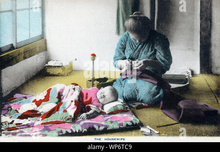 [ 1900 - Japon ] Couture mère japonaise - une femme au foyer, c'est ce qui ressemble à une couture obi (ceinture de kimono), tout en restant assis sur le tatami (tapis de riz) dans sa maison. Un bébé dort sur un futon (matelas japonais) en face d'elle. Rues japonais utilisé pour être plein de vendeurs colportant tout, de la nourriture à des paniers à la médecine. À partir de la série de cartes 10 hommes de travail au Japon. 20e siècle vintage carte postale. Banque D'Images