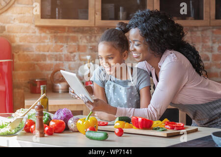 Maman et sa fille la lecture sur tablette Recette cuisine à Banque D'Images