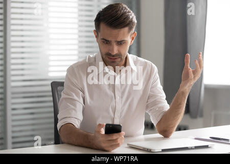 Les jeunes hommes en colère manager agacé par broken téléphone mobile. Banque D'Images