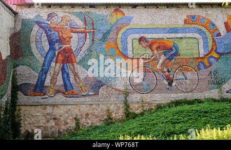 Murs de mosaïque soviétique en réparation représentant des sports sur la construction dans le complexe sportif de SKA à Lviv, Ukraine. Cyclisme et tir à l'arc Banque D'Images