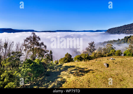 Les nuages blancs épais brouillard envahissant la vallée de kangourou et couvrant ferme agricole entre les chaînes de montagnes de grès sur un matin ensoleillé. Banque D'Images