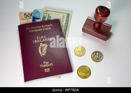 Concept de voyage avec bordeaux ou rouge bordeaux passeport irlandais, Stamp et devises affichées sur un fond uni Banque D'Images