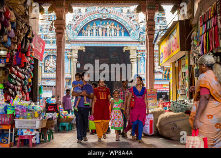 Madurai, Tamil Nadu / Inde - Janvier 14, 2016 : une famille indienne, promenades à travers une arche occupés par des boutiques, avec le célèbre Temple Meenakshi derrière. Banque D'Images