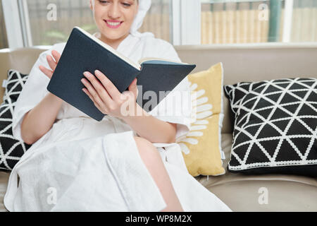 Ambiance souriante Jeune femme lisant un livre après la prise de baignoire à la maison Banque D'Images