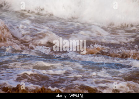 Après-midi forte marée, marée avec des vagues se brisant sur les rochers sur les rochers avec de fortes vagues écumeuses, un ressac, un lavage de côté. Du vrai en colère les vagues. Banque D'Images