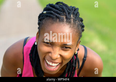 Portrait d'une jeune femme sportive africaine de flexion vers l'avant de rire à l'appareil photo Banque D'Images