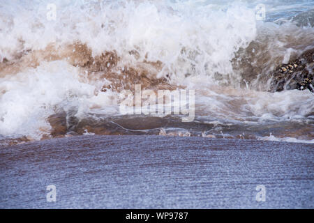 Après-midi forte marée, marée avec des vagues se brisant sur les rochers sur les rochers avec de fortes vagues écumeuses, un ressac, un lavage de côté. Du vrai en colère les vagues. Banque D'Images