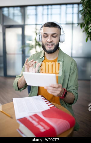 Étudiant étranger barbu de répéter en langue étrangère après l'enregistrement Banque D'Images