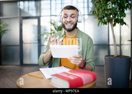 Étudiant étranger barbu ayant leçon audio en langue étrangère Banque D'Images