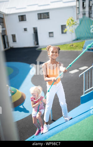 Dark-skinned girl climbing la corde avec son ami Banque D'Images