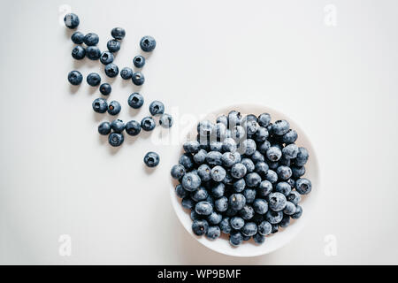 Close-up d'une plaque avec les bleuets et baies à proximité sont dispersées sur un fond blanc. Source de vitamines et de régime alimentaire. Banque D'Images