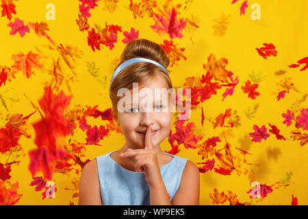 Petite fille dans un costume de princesse Cinderella à la chute des feuilles en automne. L'enfant présente un signe chut. Concept pour l'automne, maison de vacances, halloween, vente. Banque D'Images