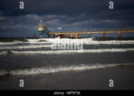 Réflexions lumineuses sur la télécabine de plongée à l'embarcadère de Zingst en face d'un ciel sombre et vagues de mer rompant en premier plan lors d'une journée de tempête. Banque D'Images