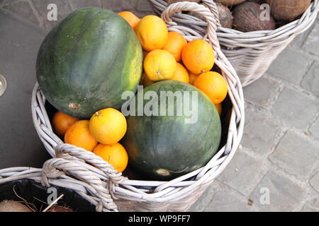 Un panier plein de melons et des oranges Banque D'Images