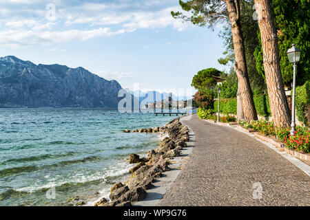 Il s'agit d'une photo d'un chemin qui longe les rives du lac de Garde. Le Village de Malcesine peut bee vu dans la distance Banque D'Images