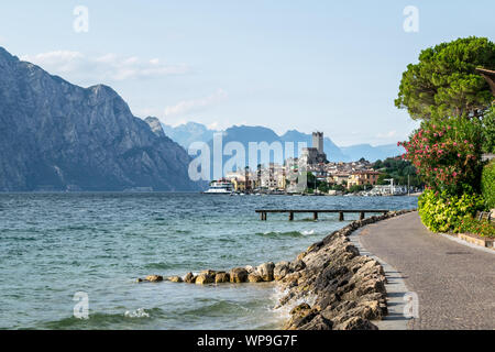 Il s'agit d'une photo d'un chemin qui longe les rives du lac de Garde. Le Village de Malcesine peut bee vu dans la distance Banque D'Images