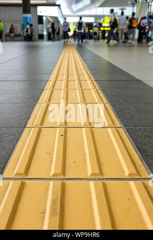 Lignes jaunes appelés "indicateurs tactiles de la surface du sol" (TGSI) ou blocs tenji. Dans la gare d'Osaka, à Osaka au Japon. Banque D'Images