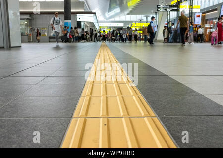 Lignes jaunes appelés "indicateurs tactiles de la surface du sol" (TGSI) ou blocs tenji. Dans la gare d'Osaka, à Osaka au Japon. Banque D'Images