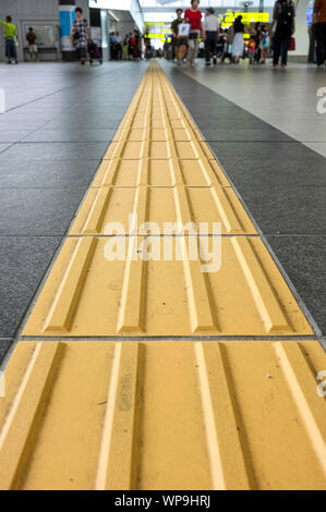 Lignes jaunes appelés "indicateurs tactiles de la surface du sol" (TGSI) ou blocs tenji. Dans la gare d'Osaka, à Osaka au Japon. Banque D'Images