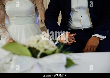 Le jeune couple est titulaire mains pendant le mariage Banque D'Images