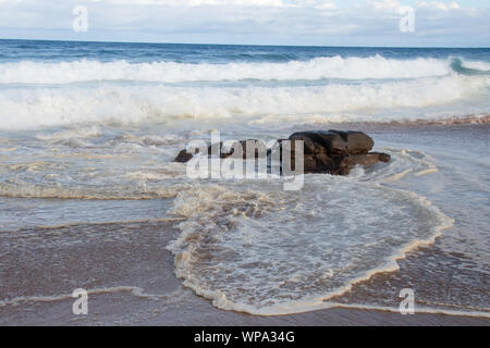 Marée est en. Cercle vicieux des vagues avec la marée montante s'écraser sur le rivage avec un très fort ressac. Le surf est mousseux le soleil de l'après-midi. Banque D'Images