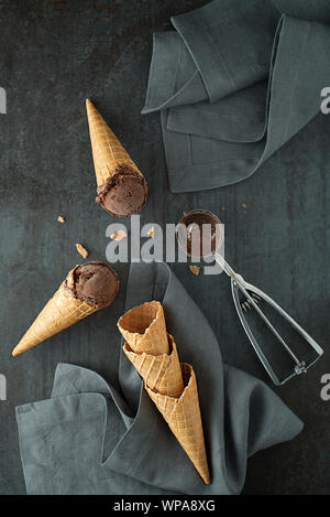 Boules de glace au chocolat, creusées dans de waffle cônes avec un ustensile d'argent Banque D'Images