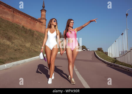 Deux copines femmes sœurs en été en ville, un maillot blanc et rose, à pied, vous pourrez vous détendre, marcher sur Fin de semaine. Bronzer en toute sécurité avec une assurance profitez de l'été. Modern Banque D'Images