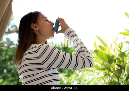 Santé et médecine - Jeune fille à l'aide Asthme inhalateur bleu pour prévenir une attaque d'asthme. Produits pharmaceutiques pour prévenir et traiter l'asthme. Banque D'Images