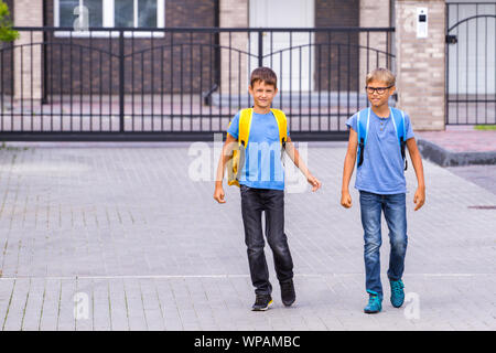 Deux shoolboys heureux avec sacs à dos aller à l'école le matin. Banque D'Images
