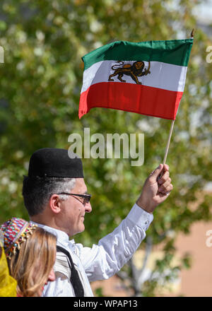 Un homme iranien vagues fièrement 'Lion-et-soleil' (Shir o Khorshid) drapeau du haut d'un flotteur en haut sur Persan Yonge dans son défilé de 1ère année. Banque D'Images