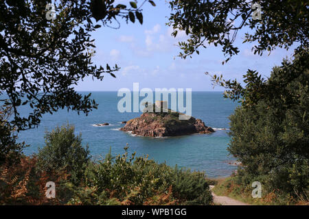 Portelet Tower, sur une île au large de Portelet Bay, comme vu à travers un cadre d'arbres, Jersey, Channel Islands. Banque D'Images