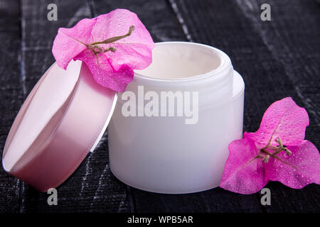 Pot de crème naturelle avec des fleurs roses sur fond noir. Cosmétiques Bio concept Banque D'Images