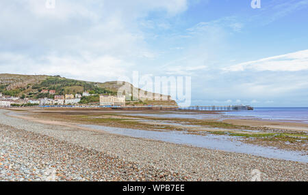 Une vue de la rive et courbée du Llandudno pier. Le grand orme pointe est dans la distance et un ciel bleu est au-dessus. Banque D'Images