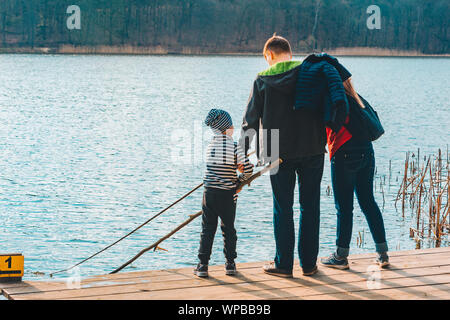 Père et Mère avec enfant Garçon jouant avec banc près de l'eau Banque D'Images