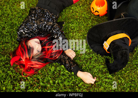 Voir ci-dessus portrait of cute little girl wearing costume Halloween allongé sur l'herbe verte, copy space Banque D'Images