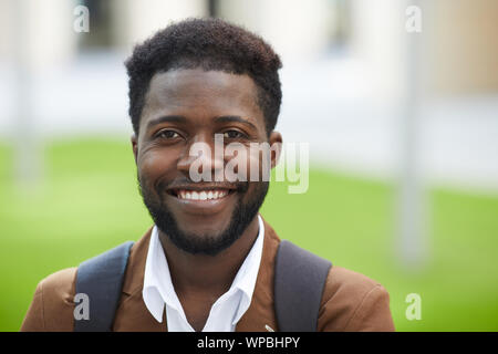 Head and shoulders portrait of handsome man smiling afro-américaine joyeusement à huis clos tout en se posant à l'extérieur dans street, copy space Banque D'Images