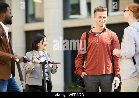 Groupe de jeunes contemporains bavarder dans la rue de la ville, l'accent sur beau jeune homme de communiquer avec des amis à l'extérieur, copy space Banque D'Images