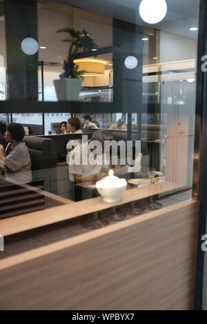 MATSUYAMA, JAPON - 20 juil 2019 : un gros plan sélectif vertical shot d'un homme assis dans un café à proximité d'autres personnes de lire le journal Banque D'Images