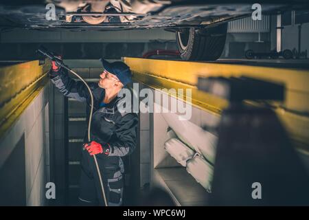 Mécanicien Auto Service Inspection de véhicule moderne sous le chariot. Emploi de l'industrie automobile. Banque D'Images