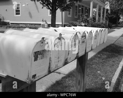 Neuf boîtes aux lettres typiques sur une rue latérale du New Jersey en noir et blanc avec un drapeau américain en arrière-plan. Banque D'Images